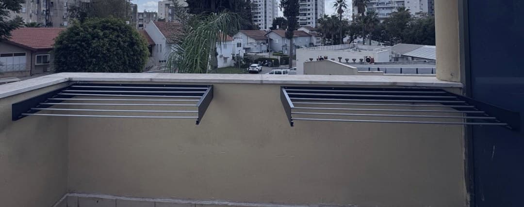 המתלה פתוח על קיר המרפסת, שבעה מוטות פרושים